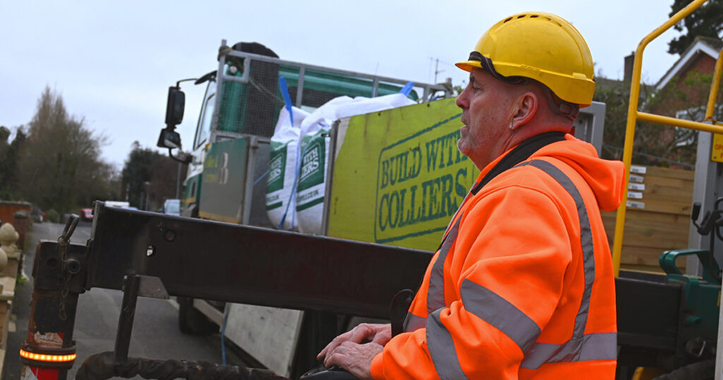 Man wearing hard hat next to lorry