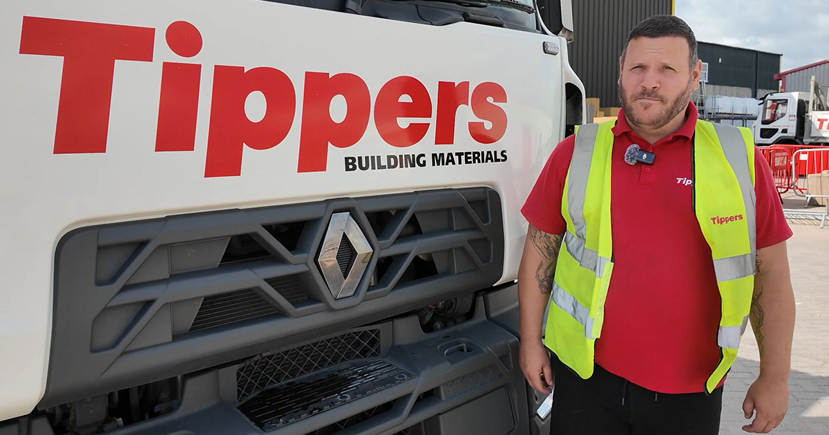 Man in high vis jacket standing next to a Tippers lorry
